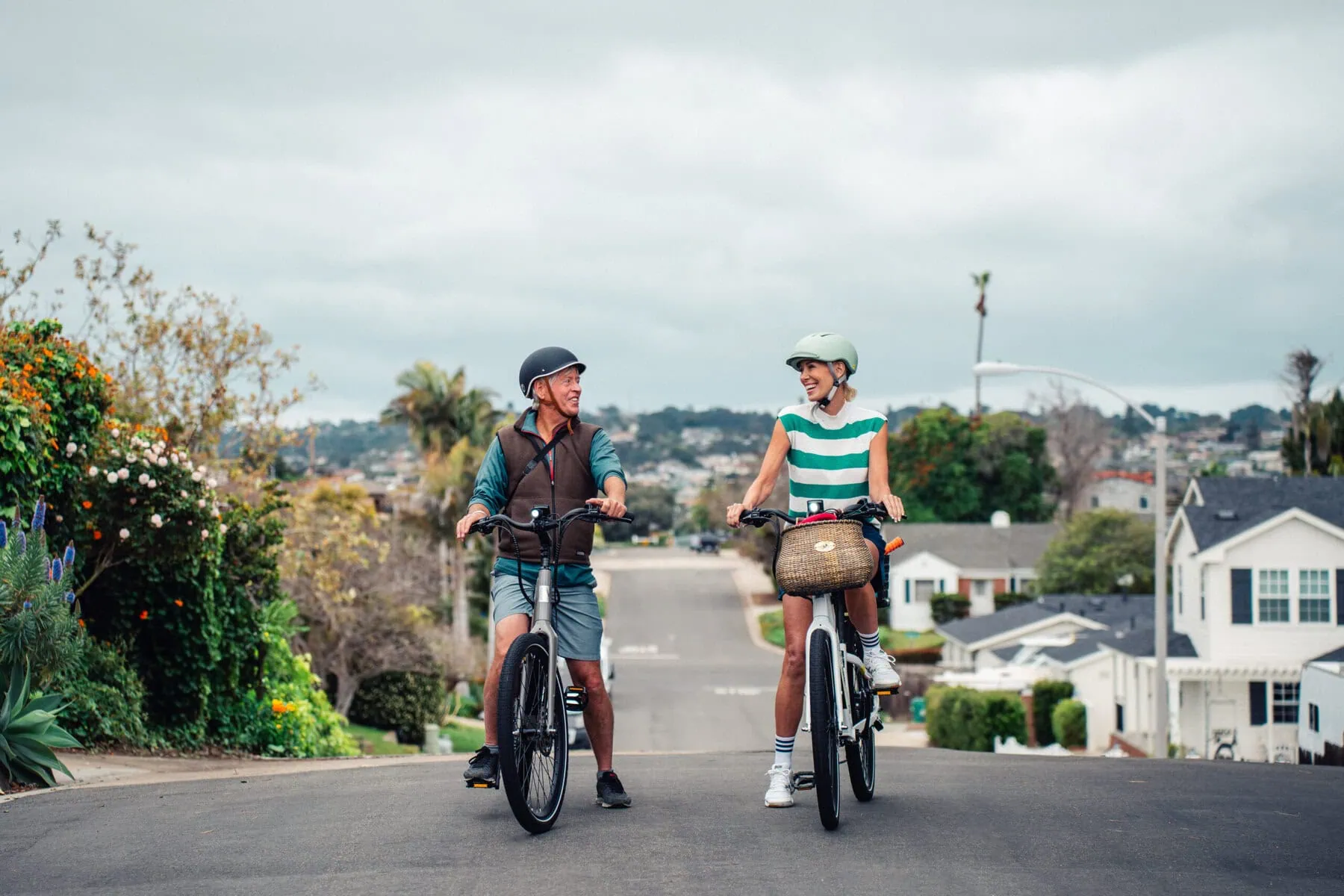 a man and woman riding e-bikes on a street