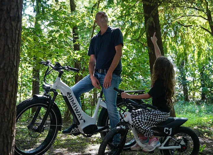 a man and girl sitting on e-bikes in the woods