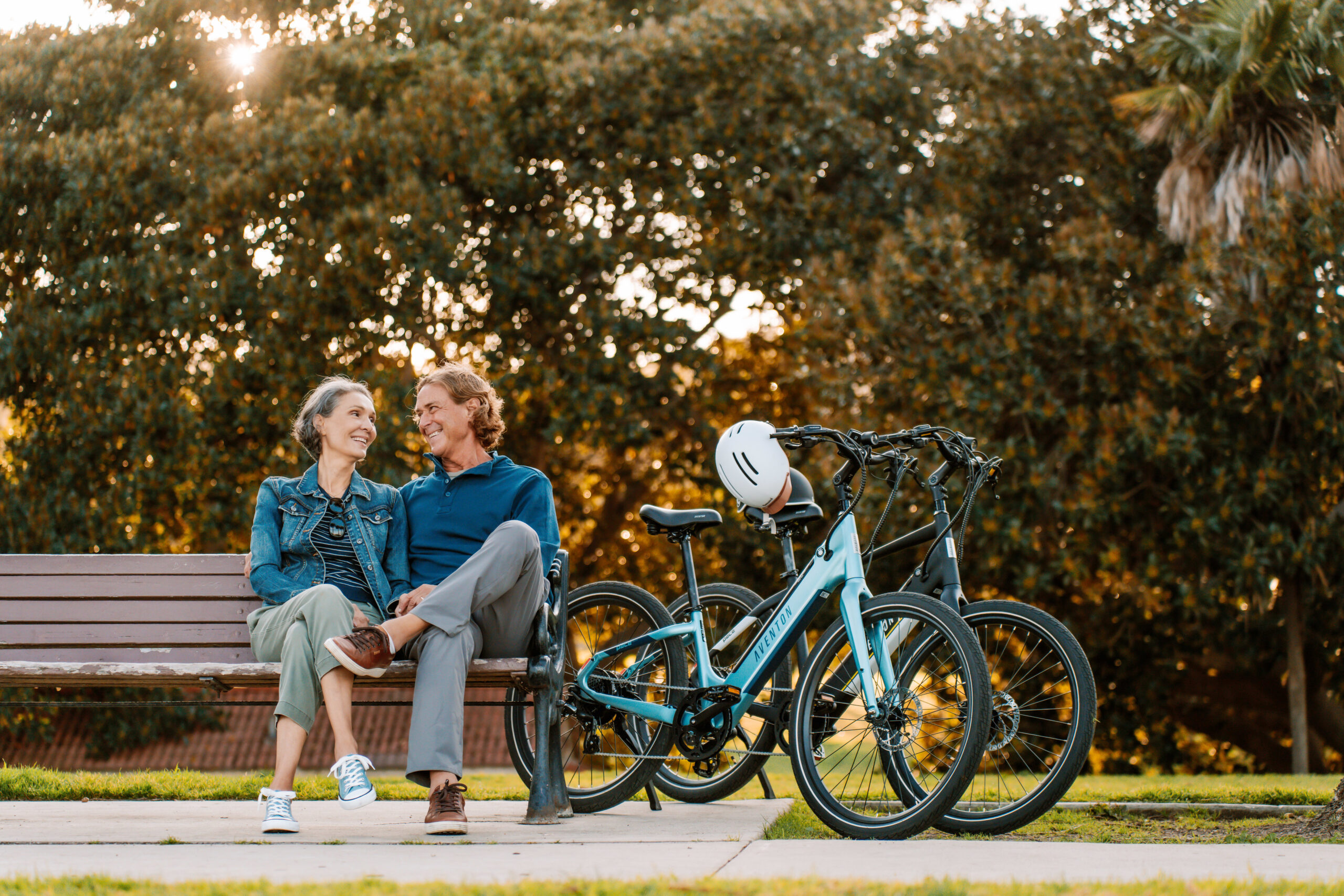 a man and woman sitting on a bench with bicycles in the background