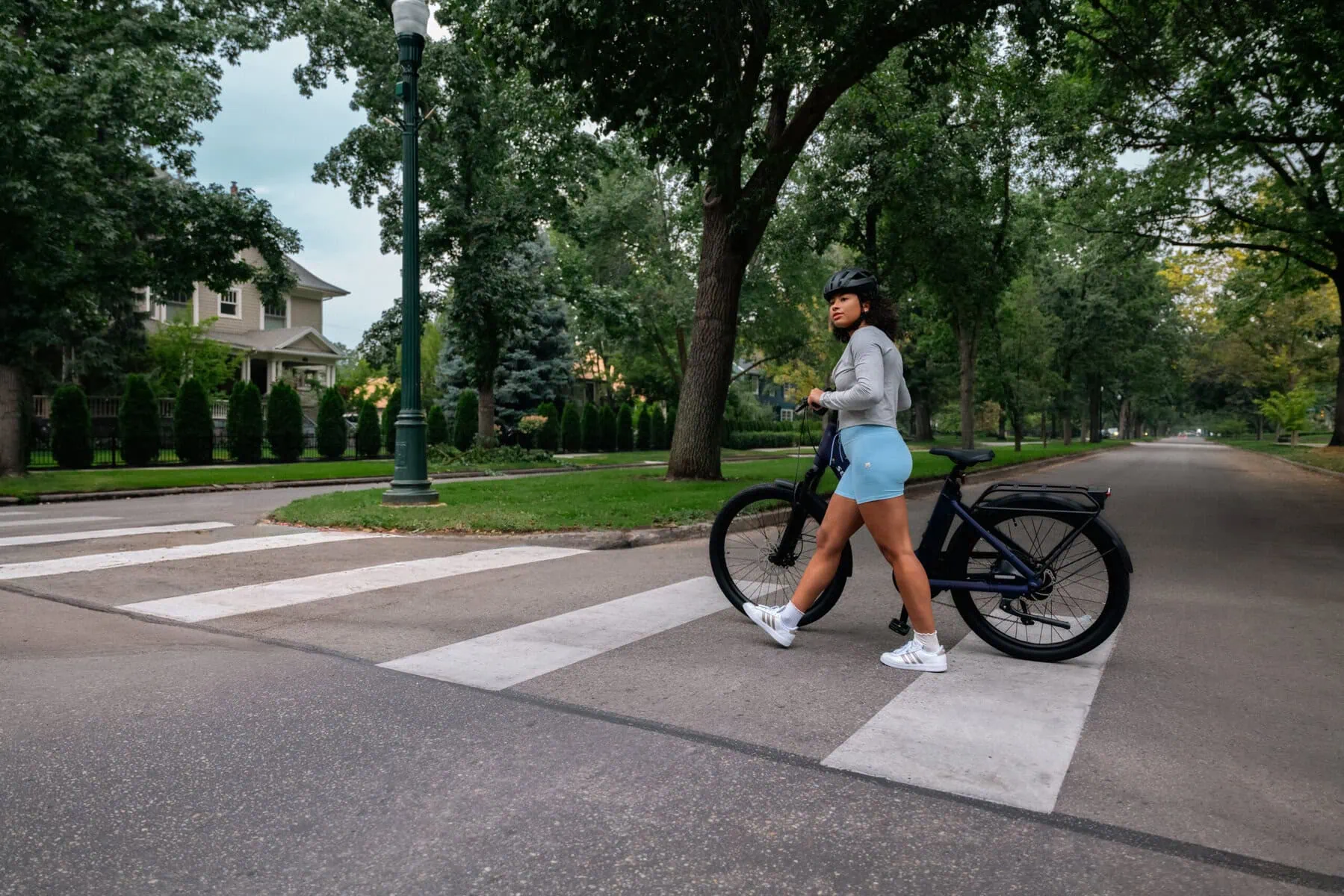 Segway EBike Myon Blue woman pushing the ebike walking crossing the street