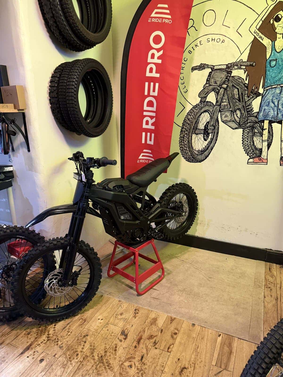 Let's Roll Lancaster shop corner with E Ride Pro banner, tires on wall, and shop mural
