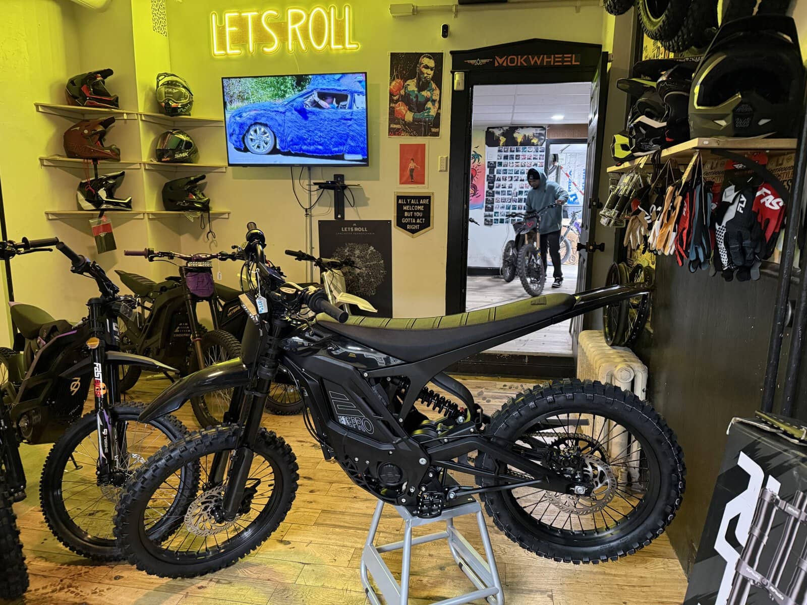 Let's Roll Lancaster e-bike shop interior with neon sign and E Ride Pro dirt bikes