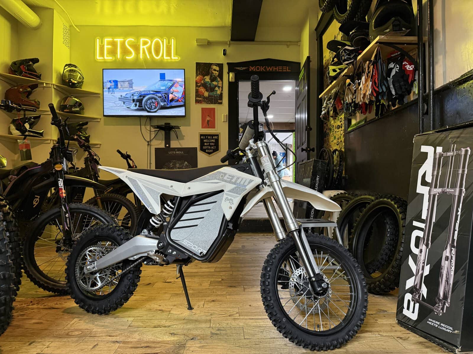 Let's Roll Lancaster e-bike shop interior with neon sign and electric dirt bikes on display