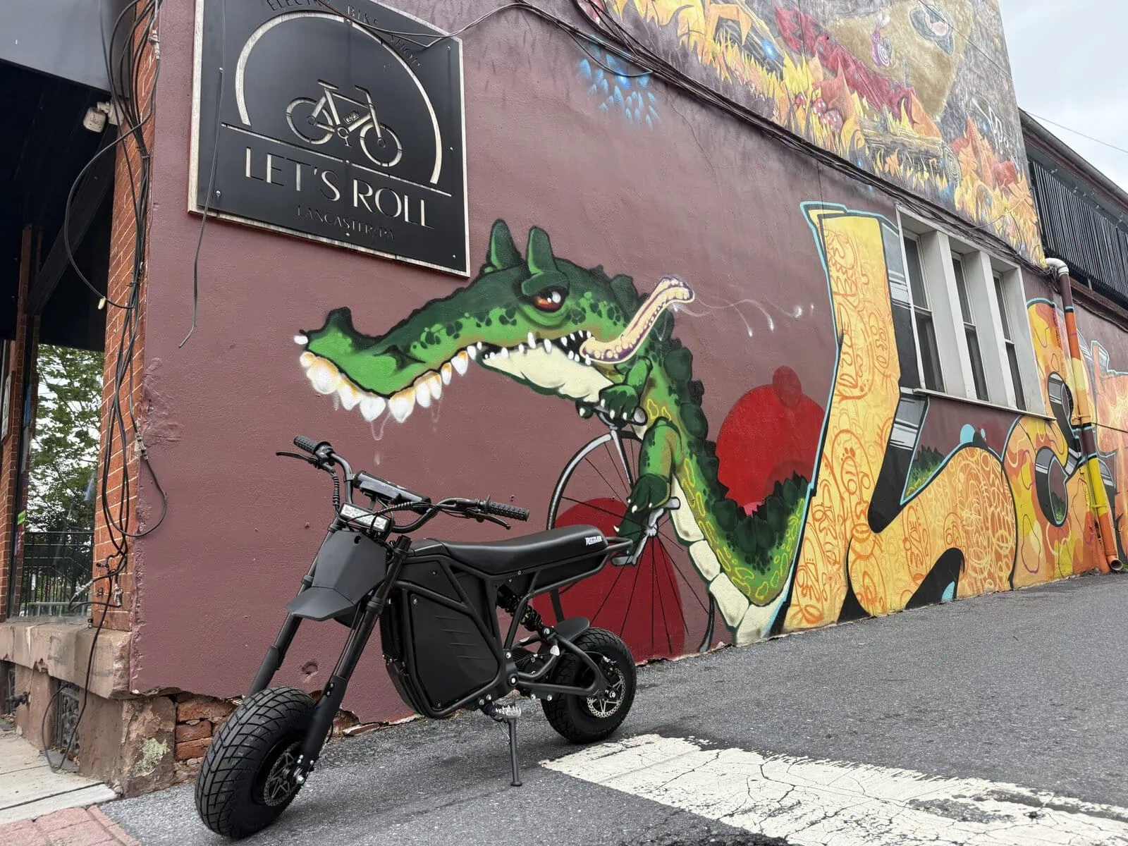 Let's Roll Lancaster storefront exterior with signage and e-bike parked in front of mural