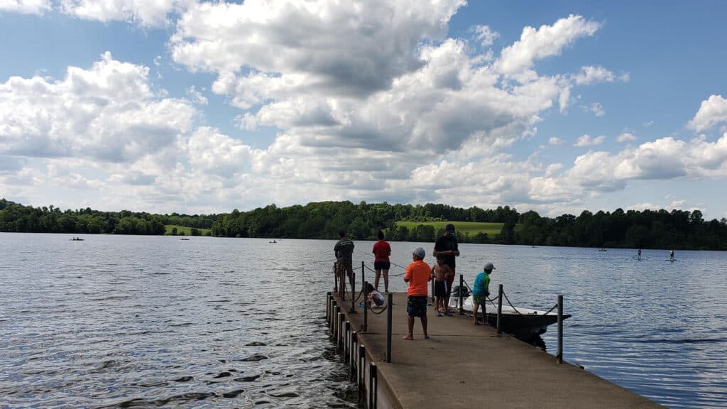 People fishing from a wooden pier on Marsh Creek Lake under a partly cloudy sky