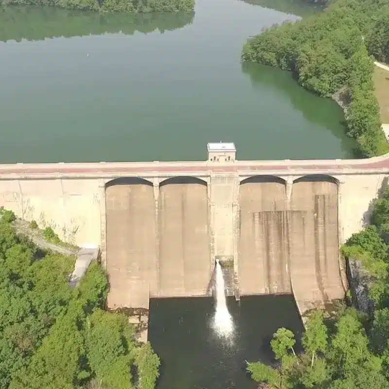 Aerial view of the Prettyboy Reservoir dam with water discharging below and forested shoreline behind
