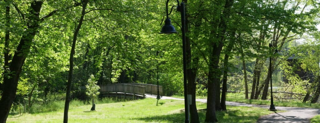 Wooden footbridge and lamp posts along a shaded stretch of the Schuylkill River Trail in spring
