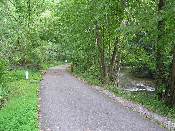 Paved Struble Trail running alongside the East Branch Brandywine Creek through summer woods